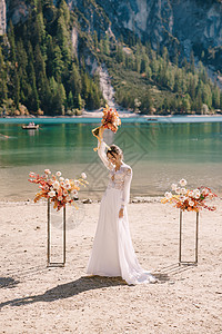 在意大利的 美丽的新娘穿着带袖子和蕾丝的白色连衣裙 在拱门的背景上放着一束黄色的秋天花束参加仪式 在欧洲的目的地婚礼 在 Bra图片