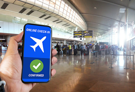 一个拿着手机的男人的手 在机场的屏幕上显示在线登记确认信息图片