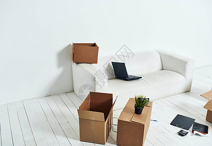 带有白色沙发拆开办公室移动的盒子船运笔记本服务开箱纸板企业家男人包装搬迁人士图片