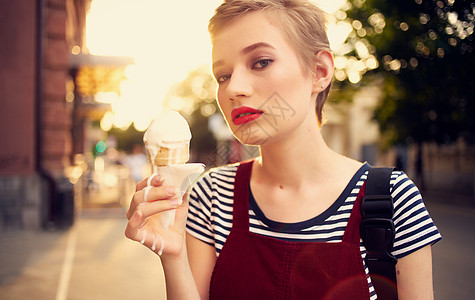 长短头发吃冰淇淋的漂亮女人 在户外休闲散步甜点旅行女性微笑快乐潮人眼镜街道奶油乐趣图片