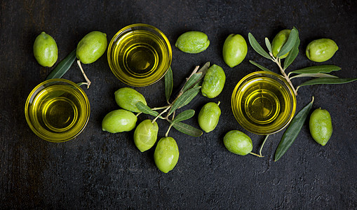 黑色背景的橄榄油和橄榄枝收成石头树叶瓶子玻璃油壶迷迭香水果烹饪桌子图片