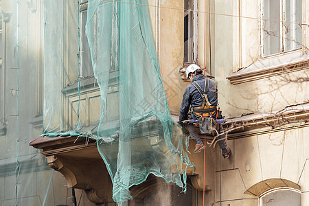 一名男子用悬吊绳修理房屋的外墙建设者窗户服务装修损害建筑危险工人绳索登山者图片