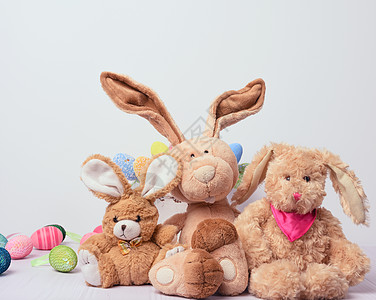 三包玩具 兔子坐在白色背景上 在装饰复活节鸡蛋后面图片