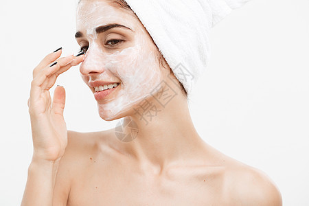 美容护肤概念美丽的白种女人面部肖像在她的面部皮肤白色背景上应用奶油面膜护理排毒面具治疗程序保湿毛巾药品温泉沙龙图片