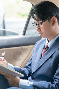 商务人士在汽车后座上打工领带出租车机动性乘客人士技术运输手机男人眼镜图片