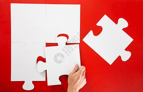 手解决红色背景上的一块拼图闲暇建造团队解决方案概念成功游戏战略挑战白色图片