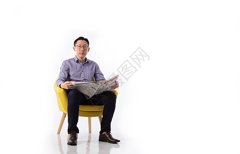 一名亚洲男子坐在扶手椅上看报纸头条杂志出版物新闻稿文章阅读生意人男性商业人士图片