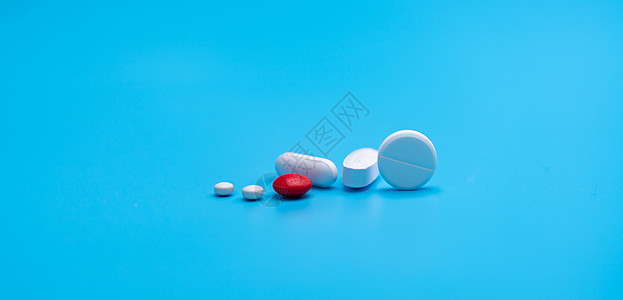 蓝色背景上的一组圆形和椭圆形白色药丸红色糖衣药丸 药房和药房部门的旗帜 医药行业 卫生保健 日常生活中的药物图片