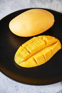 黑色盘子里的新鲜黄黄芒果水果浆果情调营养乡村热带石头玻璃食物艺术异国图片
