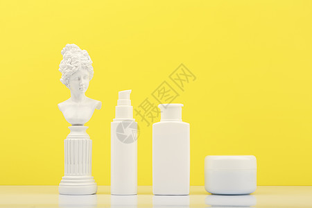 白桌上每日皮肤护理的一套美容产品 以白色石膏雕像为蓝黄色背景 (笑声)图片