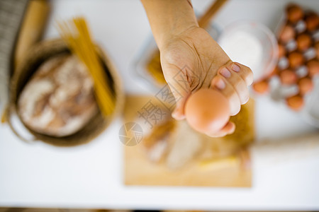 手持鸡蛋高于表上成分的雌性手小吃酵母美食面粉面条女性午餐桌子面包螺丝图片