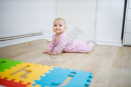 可爱的婴儿躺在木地板上面朝下女儿喜悦闲暇泡沫尿布童年孩子字母卧室幸福图片