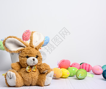 坐在白色背景和装饰多彩的东面鸡蛋上的玩具兔子季节粉色庆典娃娃绿色动物童年假期黄色传统图片