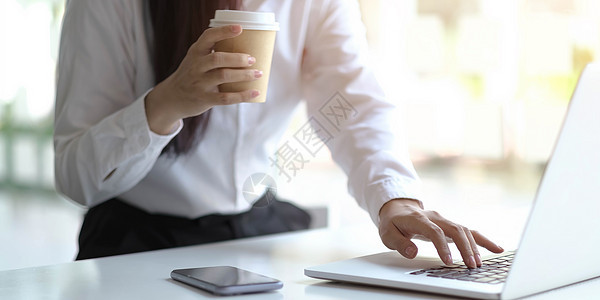 妇女握着咖啡和打字在笔记本电脑上的手 办公室工作概念 在线工作概念图片