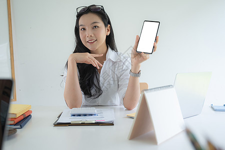 亚洲女商务人士的画像 手持智能手机 屏幕空白 在家工作 会计概念图片