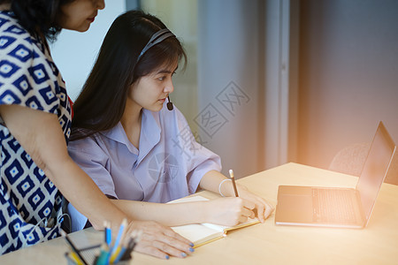 母女俩正在通过笔记本电脑在线上课 成年妇女教孩子数学 幸福的家庭图片