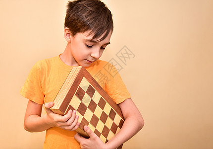 一个男孩手里握着一个棋盘 看着它学校智慧爱好男生木板游戏智力逻辑工作室人士图片