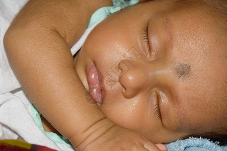 特写一个可爱的熟睡的新生婴儿的脸 在昏昏欲睡的心情昏昏欲睡的眼睛中捕捉到的甜蜜刚出生的男婴的特写肖像 手放在下巴上 正视图 儿童图片
