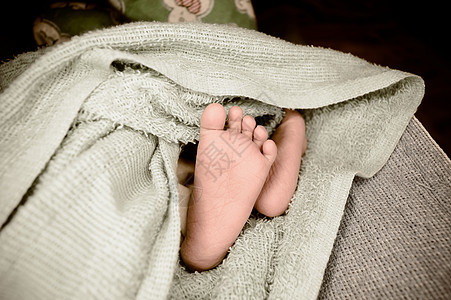 新生婴儿的脚靠拢 一个刚出生的婴儿的腿躺在柔软的婴儿毛毯上 可爱的爱情舒适背景 复古彩色图像 复制空间睡眠分娩快乐毛巾步兵摄影保图片