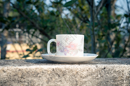 早晨阳光下的咖啡杯 夏日清新凉爽的look 带有散景背景的住宅楼屋顶梁上的热饮茶碟上的白咖啡杯图片