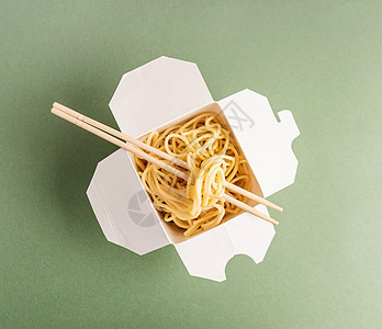 开开放的WOK纸箱 面条和筷子顶楼视图平板 绿色背景图片