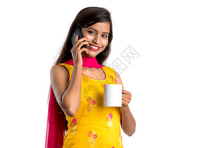 年轻漂亮女孩在喝好喝的咖啡或茶饮料的同时 呼用智能电话设备震惊八卦商业杯子金发女郎细胞办公室手机冒充乐趣图片
