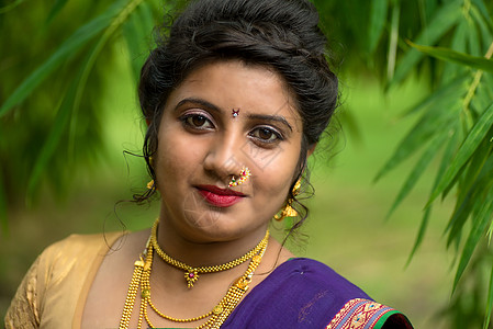 印度传统美丽的年轻女孩穿着纱丽在户外摆姿势裙子节日微笑首饰文化宗教森林手势快乐女性图片