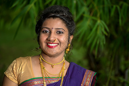 印度传统美丽的年轻女孩穿着纱丽在户外摆姿势裙子女性森林手势微笑女士首饰快乐宗教节日图片
