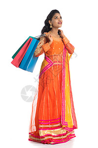 美丽的印度年轻女孩穿着传统民族服饰提着购物袋 在白色背景上被隔离冒充店铺女士裙子购物狂节日女性震惊胜利销售背景