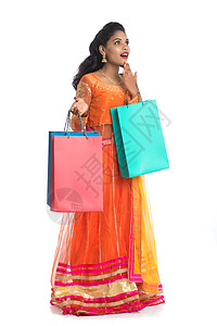 美丽的印度年轻女孩穿着传统民族服饰提着购物袋 在白色背景上被隔离节日胜利顾客裙子女性女士震惊购物狂销售冒充背景