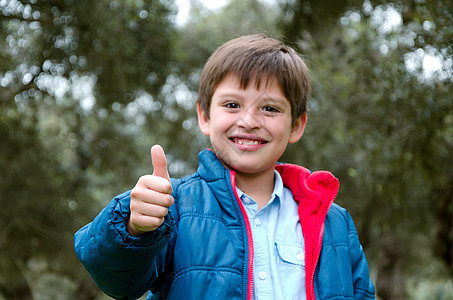 一个金发可爱男孩的肖像 抬起拇指 微笑孩子乐趣快乐喜悦相机青年男性幸福教育学校图片