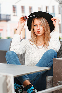 一个戴着黑帽子和太阳镜的年轻美女的肖像 美丽的女孩坐在夏日咖啡厅里娱乐女士假期街道魅力球衣潮人成人季节旅行图片
