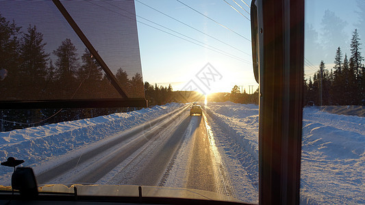 巴士日落时看到雪下的道路天空民众旅行窗户假期街道树木车辆交通驾驶图片