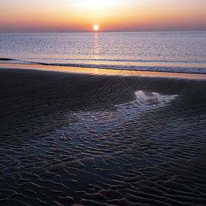 沙子中的图案和落日在水中的彩色反射海洋海岸海浪阳光天空假期季节蓝色日落支撑图片