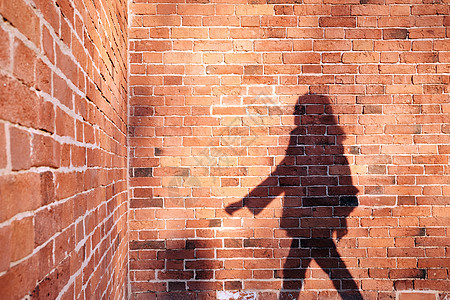 一个人在砖墙背景上的影子城市横线垂直阴影城墙成人女孩红砖长发阳光图片