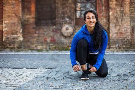 运动妇女系紧鞋带城市幸福身体活力训练享受女性生活方式跑步练习图片