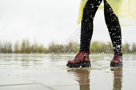 女人在雨中玩耍 在水坑里跳乐趣闲暇飞溅城市运动天气沥青训练女士赛跑者图片