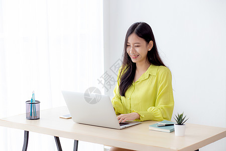 年轻的亚洲女商务人士在家庭办公室的办公桌上使用笔记本电脑工作 自由职业者在桌上的笔记本上看和打字 女性在线学习的生活方式 商业和图片