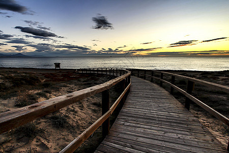 在西班牙阿利坎特的日出时 Wooden 步行走向海滩支撑太阳地平线村庄金子魔法海洋竞技场海景天空图片