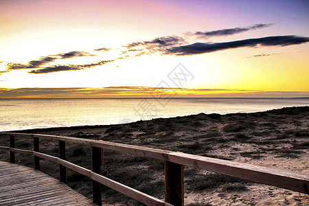 在西班牙阿利坎特的日出时 Wooden 步行走向海滩地平线金子竞技场场景天空支撑太阳海岸橙子海景图片