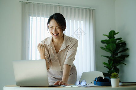 女商务人士在办公室开会 对笔记本电脑屏幕的成功感到兴奋 (掌上型电脑屏幕)图片