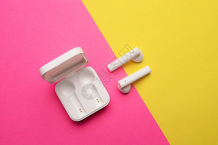 粉红色背景上的无线耳机 明亮的背景 白色耳机 蓝牙耳机 粉色和黄色背景 复制空间 现代技术立体声娱乐手机营销横幅商业互联网豆荚社图片