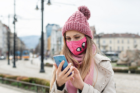 戴科罗纳面具的令人厌恶的女人在手机上检查新闻图片