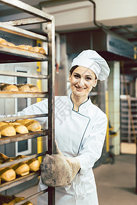 贝克女人在烤炉里用面包把床单和面包一起推食物产品味道职业烘烤工作质量制服面团女士图片