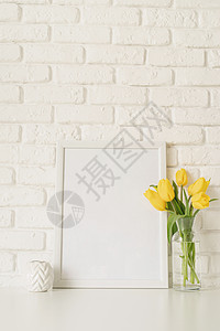 玻璃花瓶中的黄色郁金香和白砖墙背景上的空白照片框植物花朵框架季节桌子庆典礼物花瓣叶子花束图片