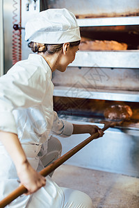 贝克在面包烤箱里放面包工业食品传统制服女士生产商业工作生意味道图片