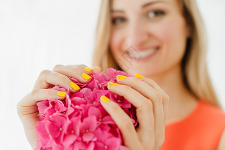 黄黄色有修指甲的妇女拿着一朵花美甲师抛光手足手指美甲沙龙美甲店情感粉色保养背景图片