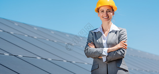 妇女投资者站在太阳能电池板前的清洁能源投资人生态人士双臂太阳系发电机农场产业过渡电气控制板图片