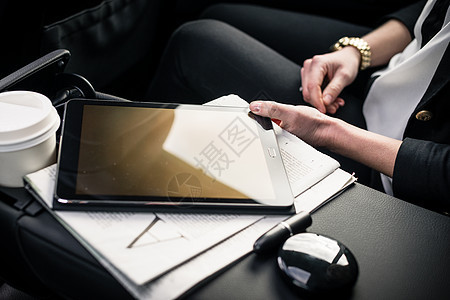 坐在汽车上与数字平板电脑相触的女商务人士图片