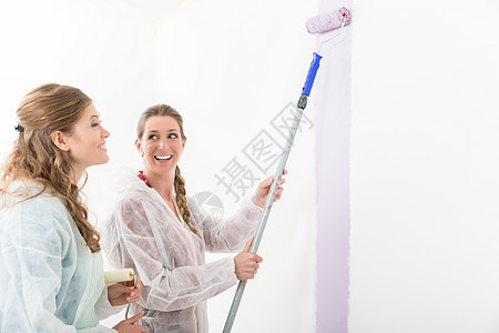 女人看着她朋友在墙上画画粉饰房子工作服务公寓女性画家微笑成人装修图片